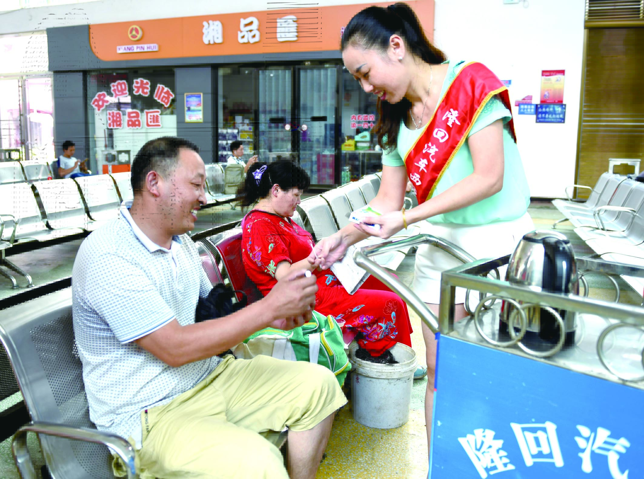 隆回分公司汽車西站工作人員正在為旅客免費(fèi)贈(zèng)送藿香正氣水。